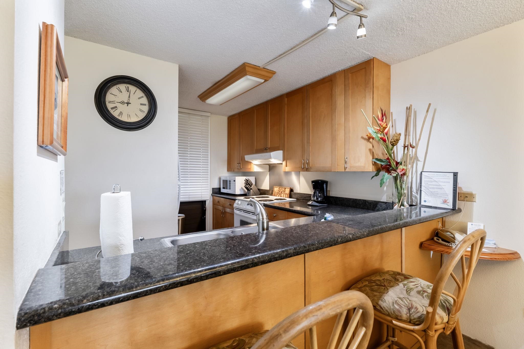 2695 South Kihei Road, Unit 4301 Kihei, HI 96753 - Photo 13 of 45 a kitchen with a table chairs and a clock on wall