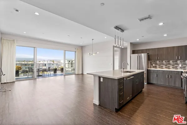 a large kitchen with stainless steel appliances a large counter top and a wooden floors