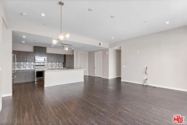 a kitchen with stainless steel appliances granite countertop a refrigerator a sink a stove and white cabinets with wooden floor