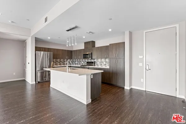 a kitchen with stainless steel appliances kitchen island wooden floors granite counter tops and a view of living room
