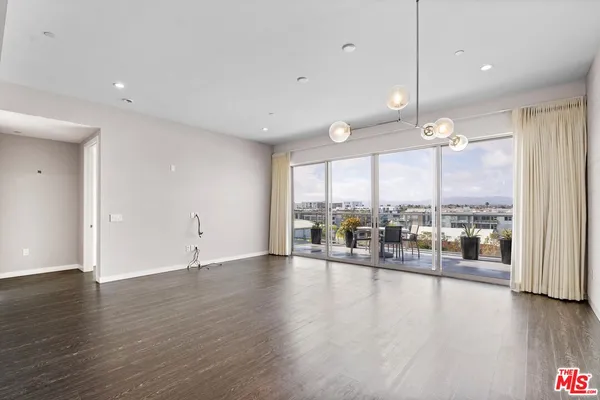 an empty room with wooden floor and large windows