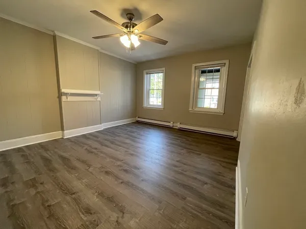 a view of an empty room with window and chandelier fan