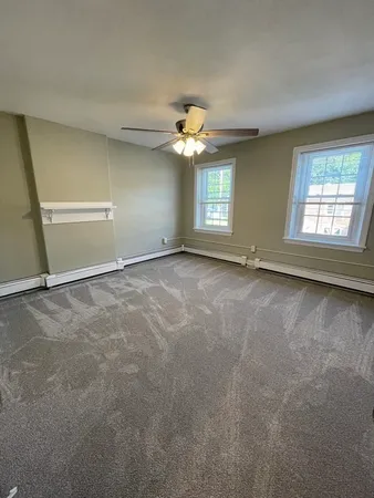 an empty room with windows and fan