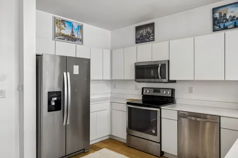 a kitchen with stainless steel appliances a refrigerator a stove and white cabinets