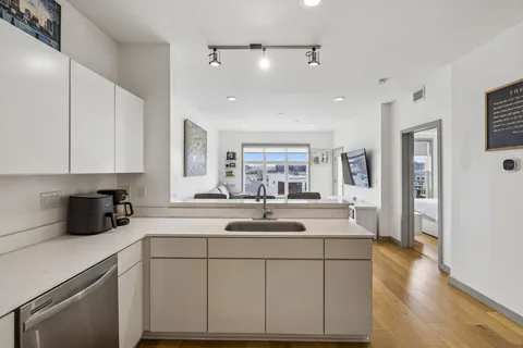 a kitchen with kitchen island a sink and white cabinets with wooden floor