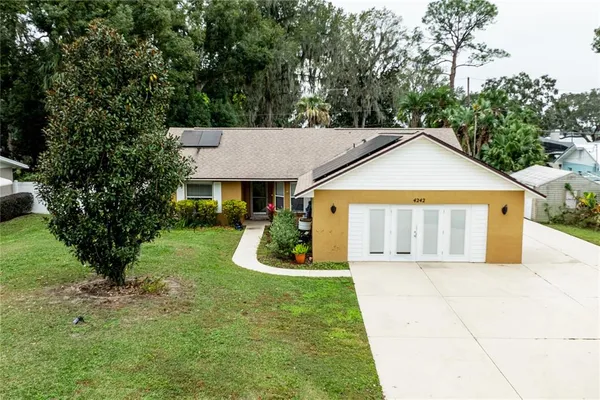 a view of a house with a yard plants and large tree