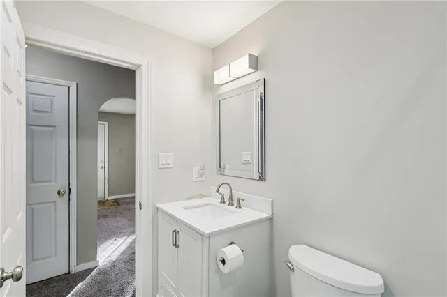 a bathroom with a toilet a sink a mirror and vanity