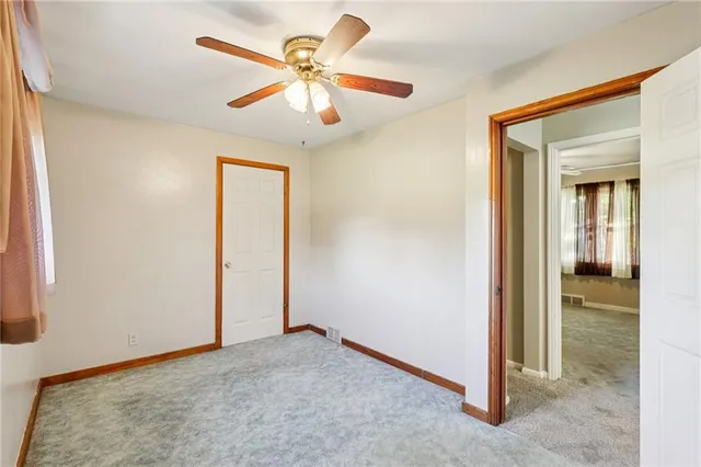 an empty room with a ceiling fan and a window