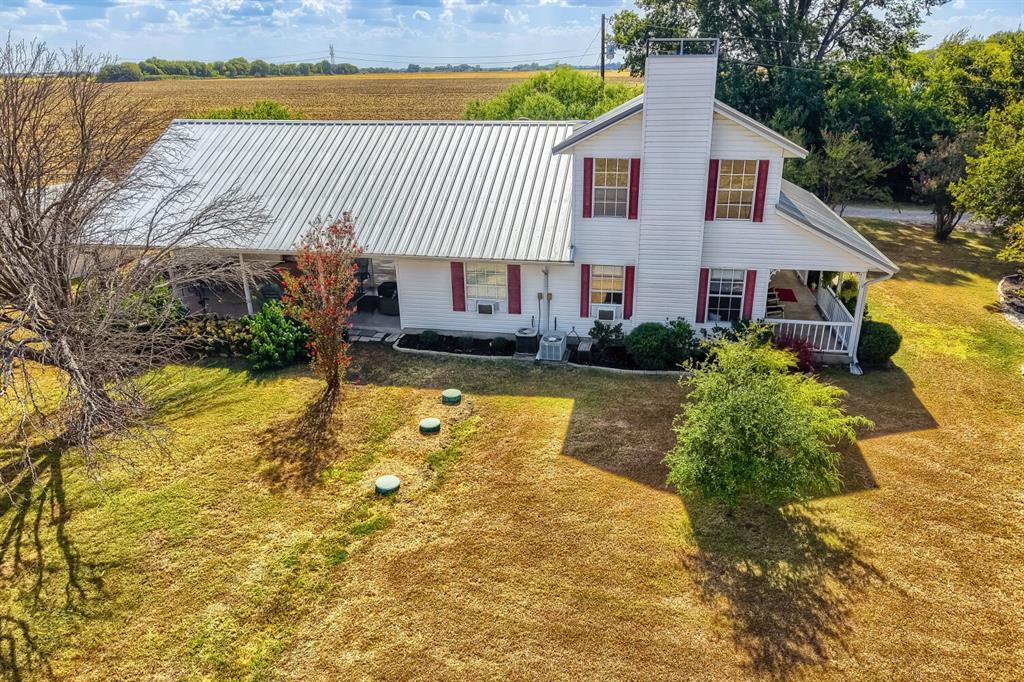 626 Epps Road Palmer, TX 75152 - Photo 30 of 40 White siding exterior with a metal roof and red shutters, featuring a covered porch with a railing and a prominent chimney structure