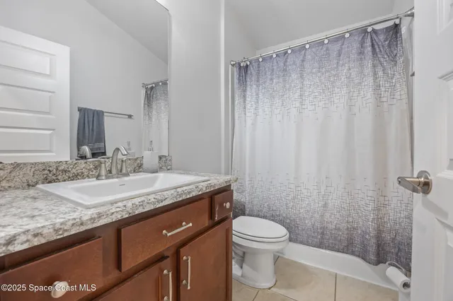 a bathroom with a granite countertop sink a toilet and shower