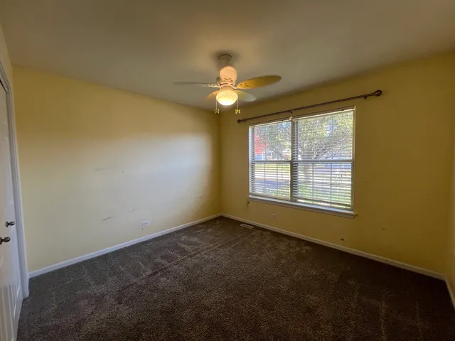 a view of an empty room with chandelier fan and a window
