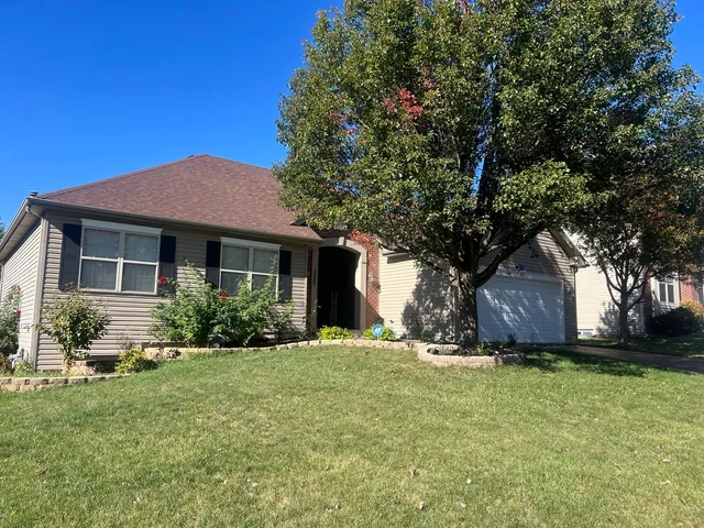 a front view of a house with a garden and tree
