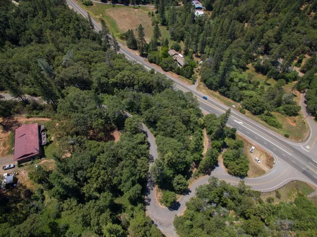 an aerial view of residential house with outdoor space and trees all around