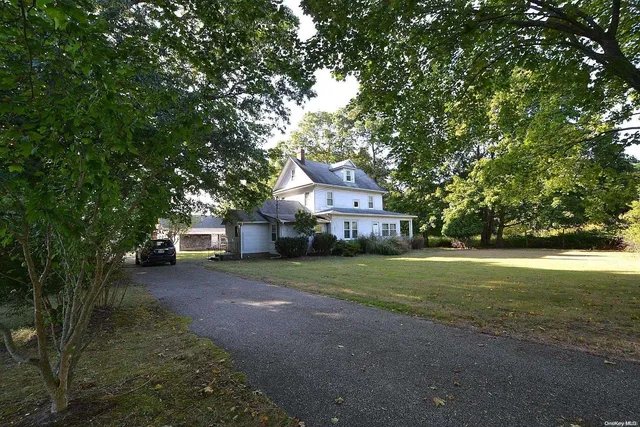 a view of a house next to a big yard with large trees
