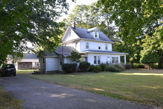 a view of a yard in front of a house with plants and large tree