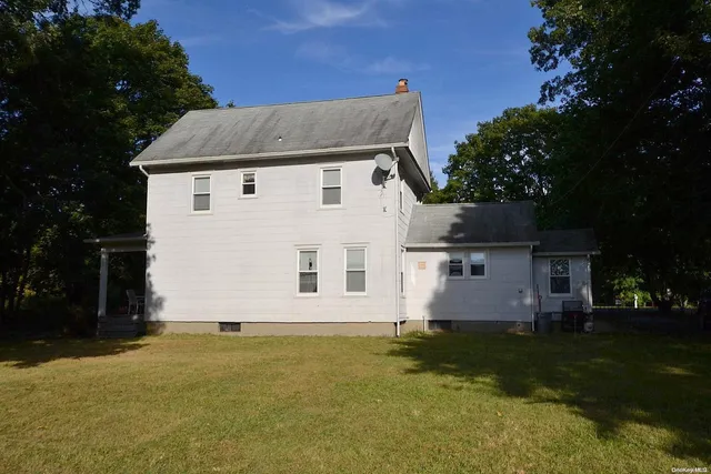a front view of house with yard and trees in the background