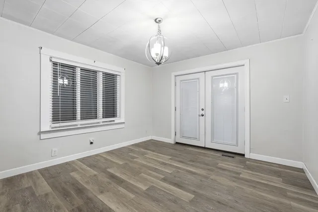 a view of an empty room with wooden floor and windows