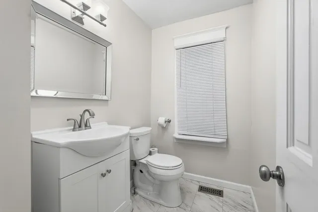 a bathroom with a toilet a sink a mirror and vanity