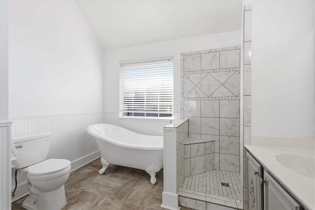 5023 Falcon Hollow Road McKinney, TX 75072 - Photo 18 of 25 Full bathroom featuring a soaking tub, wainscoting, vaulted ceiling, a tile shower, and vanity