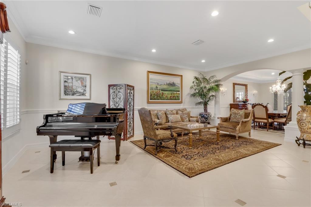 Living room featuring a chandelier, crown molding, arched walkways, light tile patterned floors, and recessed lighting