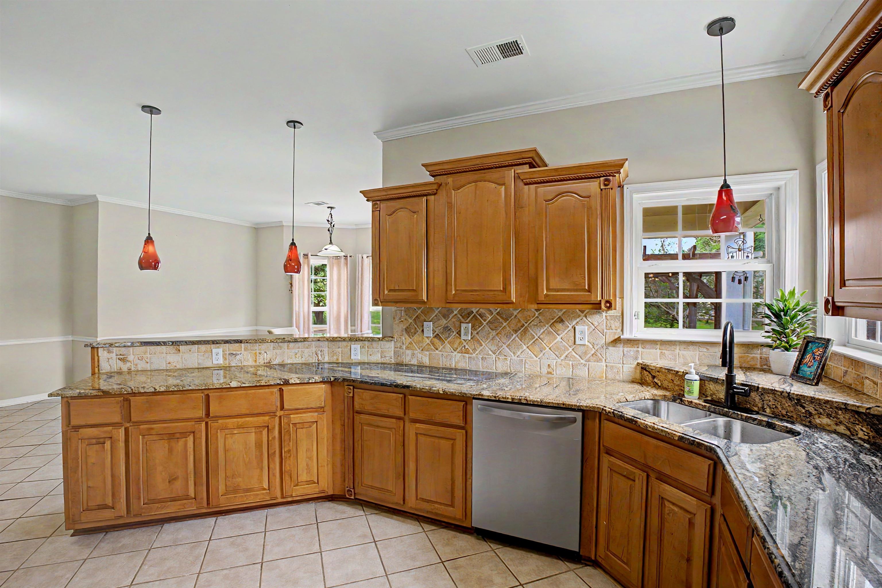 134 Rembert Drive Atoka, TN 38004 - Photo 19 of 38 Kitchen featuring granite countertops, wood cabinetry, stainless steel dishwasher, and a double basin sink with a gooseneck faucet