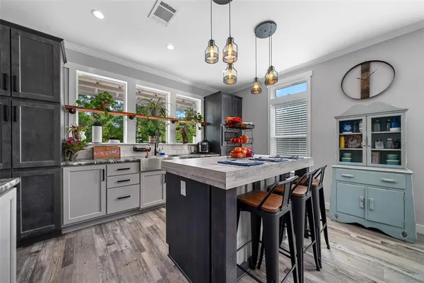 a kitchen with stainless steel appliances granite countertop a stove a refrigerator a kitchen island a dining table and chairs with wooden floor