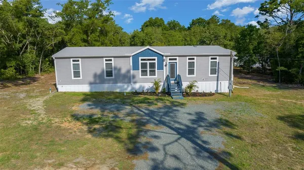 a view of a yard in front of a house with large trees