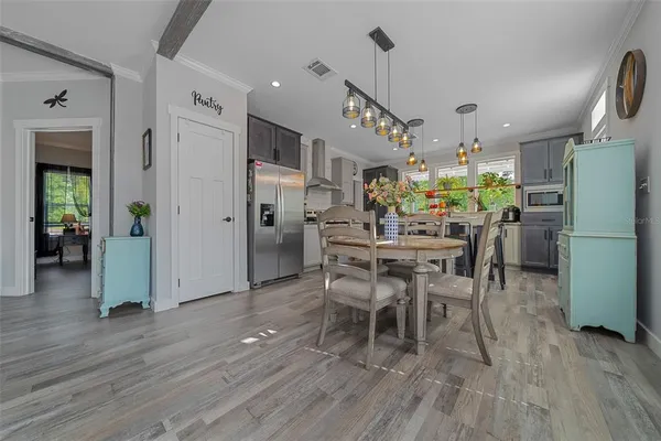 a dining room with furniture a kitchen a refrigerator and wooden floor