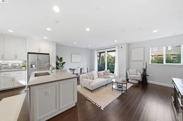 a living room with stainless steel appliances furniture and a wooden floor