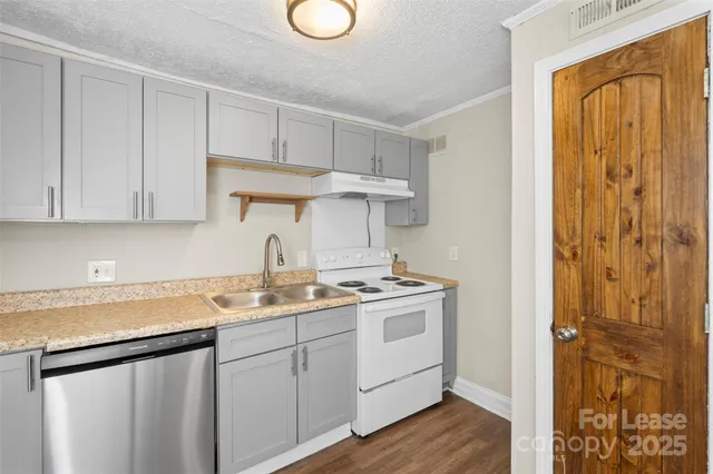 a kitchen with a sink dishwasher and cabinets with wooden floor