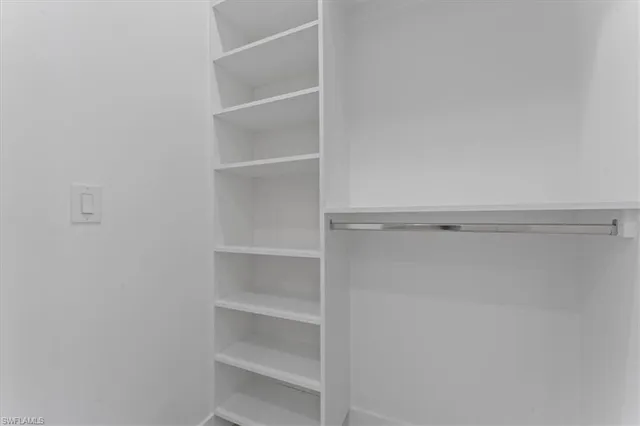 a view of walk in closet with empty racks