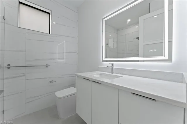 a bathroom with a granite countertop toilet a sink and a mirror