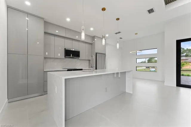 a large white kitchen with kitchen island a sink stainless steel appliances and a cabinets