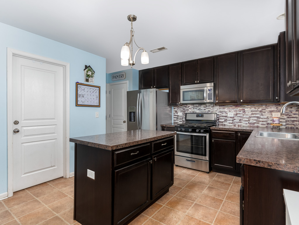 1765 Sebastian Road Woodstock, IL 60098 - Photo 9 of 25 a kitchen with kitchen island granite countertop stainless steel appliances and wooden cabinets