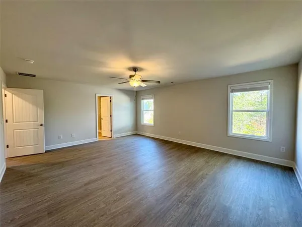 an empty room with wooden floor and windows