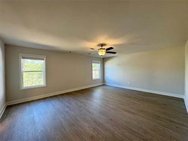 a view of an empty room with a window and wooden floor