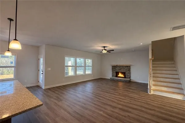 a view of an empty room with wooden floor fireplace and a window