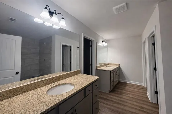 a bathroom with a granite countertop double vanity sink and mirror