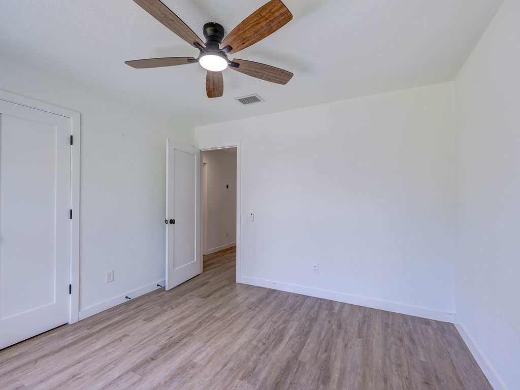 5842 Secrest Drive Austin, TX 78759 - Photo 17 of 40 An airy room with a warm wood-toned ceiling fan and durable plank flooring awaits your personal touch.