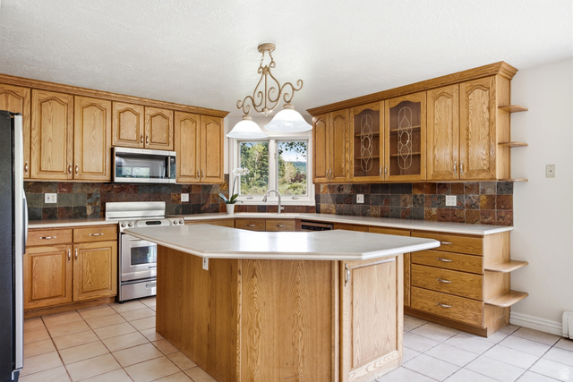 3535 Homestead Road Park City, UT 84098 - Photo 13 of 81 Kitchen featuring a central island with countertop space, light wood-finish cabinetry, stainless steel appliances, tile flooring, and a multi-toned tile backsplash