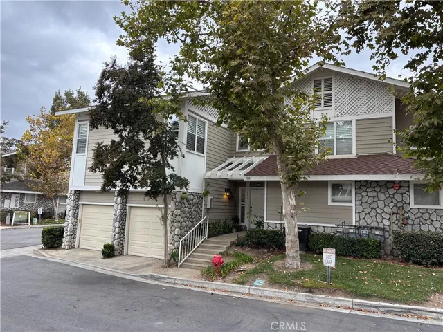 a view of a white house with large tree and plants