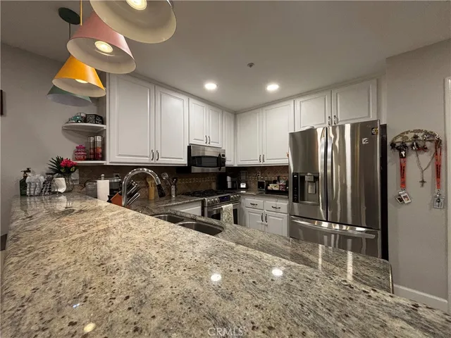 a kitchen with stainless steel appliances granite countertop a refrigerator sink and stove