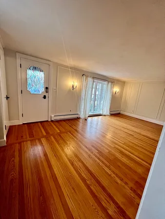 a view of an empty room with window and wooden floor
