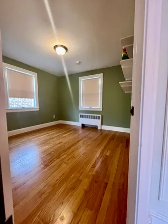 a view of empty room with window and wooden floor