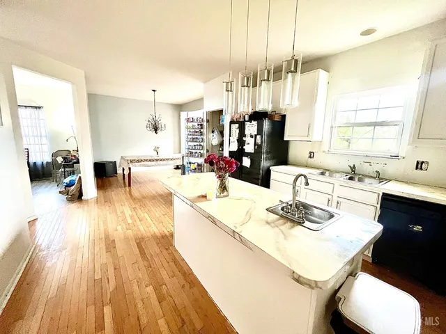 a living room with stainless steel appliances kitchen island granite countertop a sink a stove and a wooden floor
