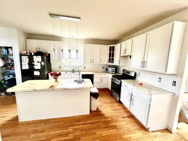 a large white kitchen with wooden floors and white appliances