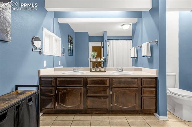 4990 Castledown Road Colorado Springs, CO 80917 - Photo 18 of 37 Bathroom with double vanity, tile patterned floors, toilet, and a sink