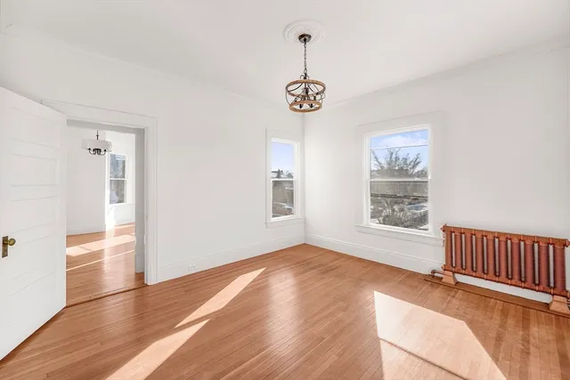 a view of an empty room with wooden floor and fan