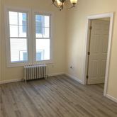 an empty room with wooden floor chandelier fan and windows