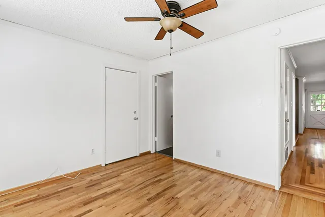 a view of a room with wooden floor and a ceiling fan
